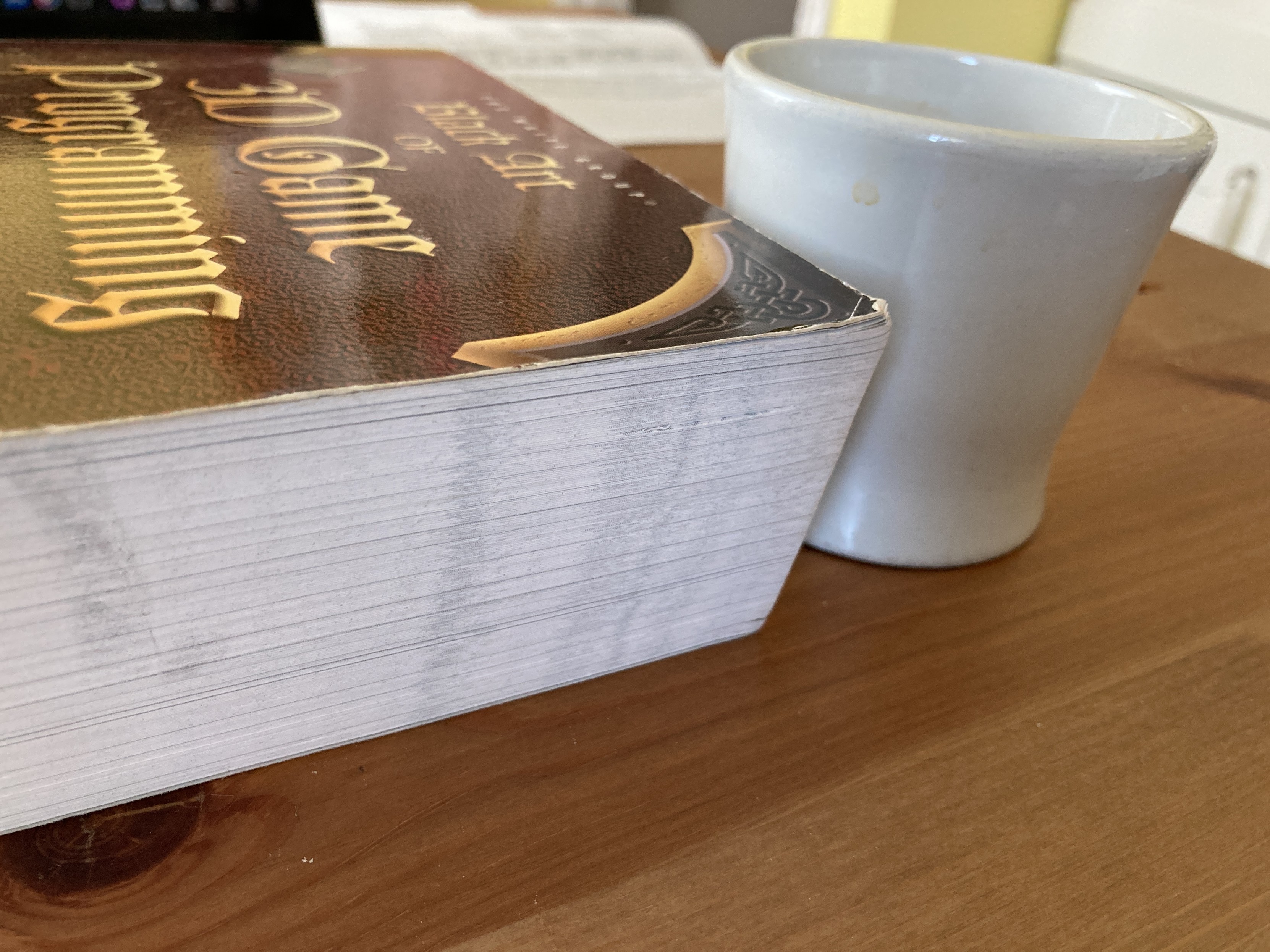 A four-inch-tall coffee cup sits beside a girthy copy of the book, rising 2/3rds up the cup's side.